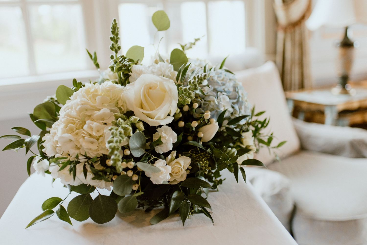 white-rose-wedding-bouquet-laying-on-table-romantic-wedding-venue-rowena's-inn