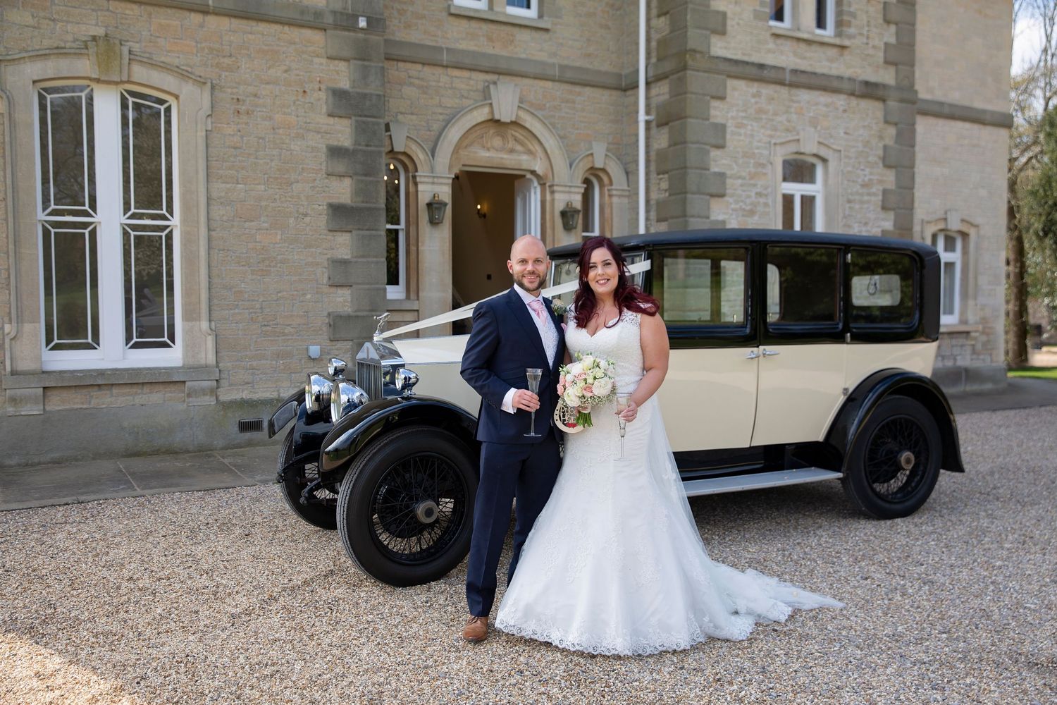 front of St Tewdrics House with bride and groom and their wedding car