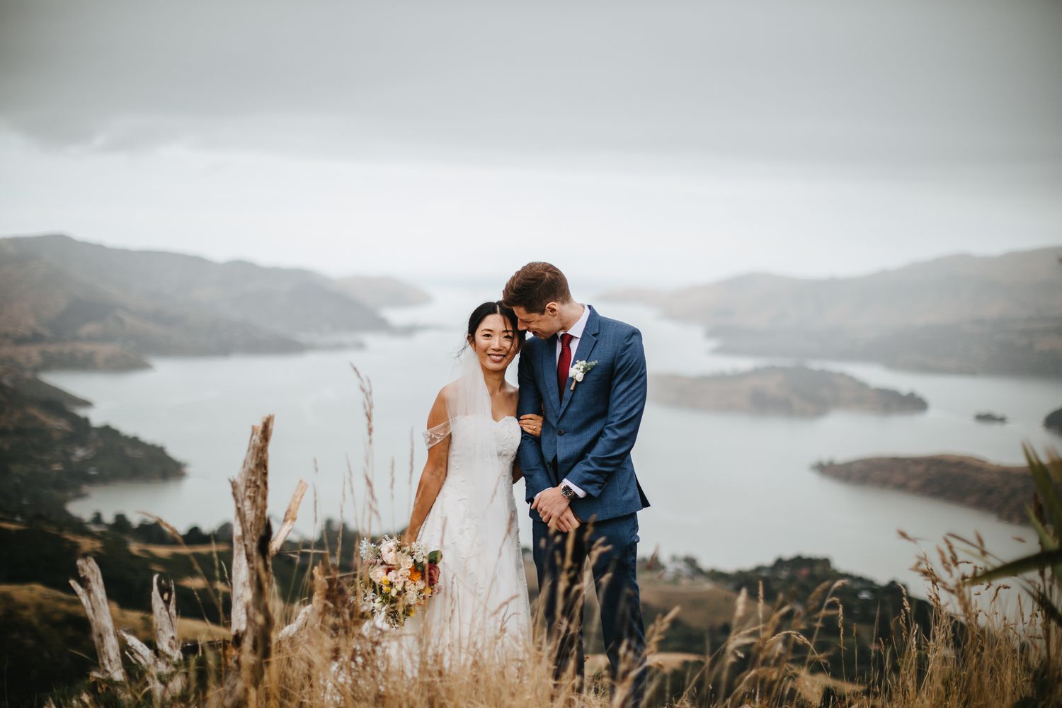 Bride and Groom posing in front of view point Te Rāpaki-o-Te Rakiwhakaputa hills in Christchurch