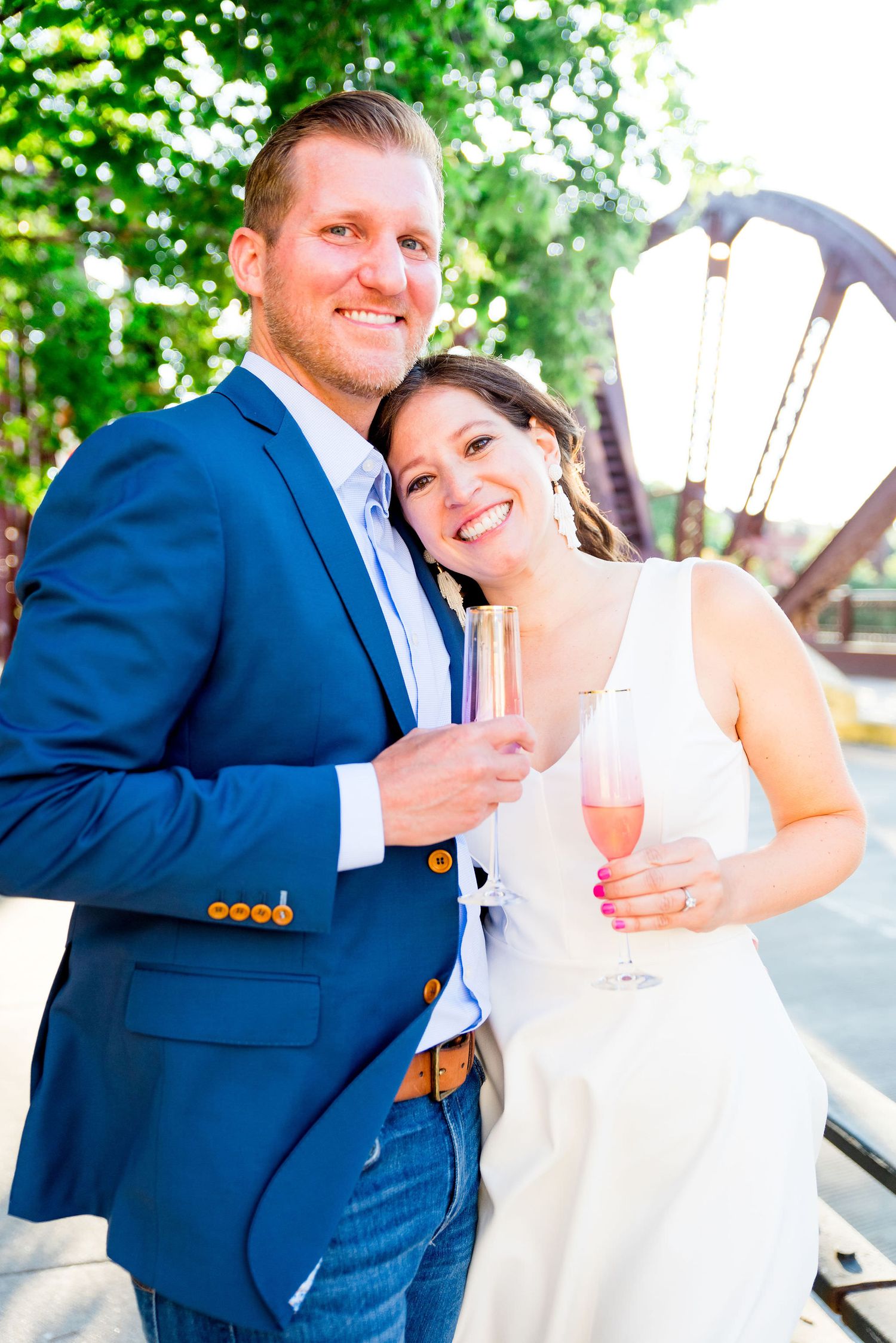 engaged man and woman holding champagne glasses and smiling at sunset at Kinzie St Bridge in River North, Chicago