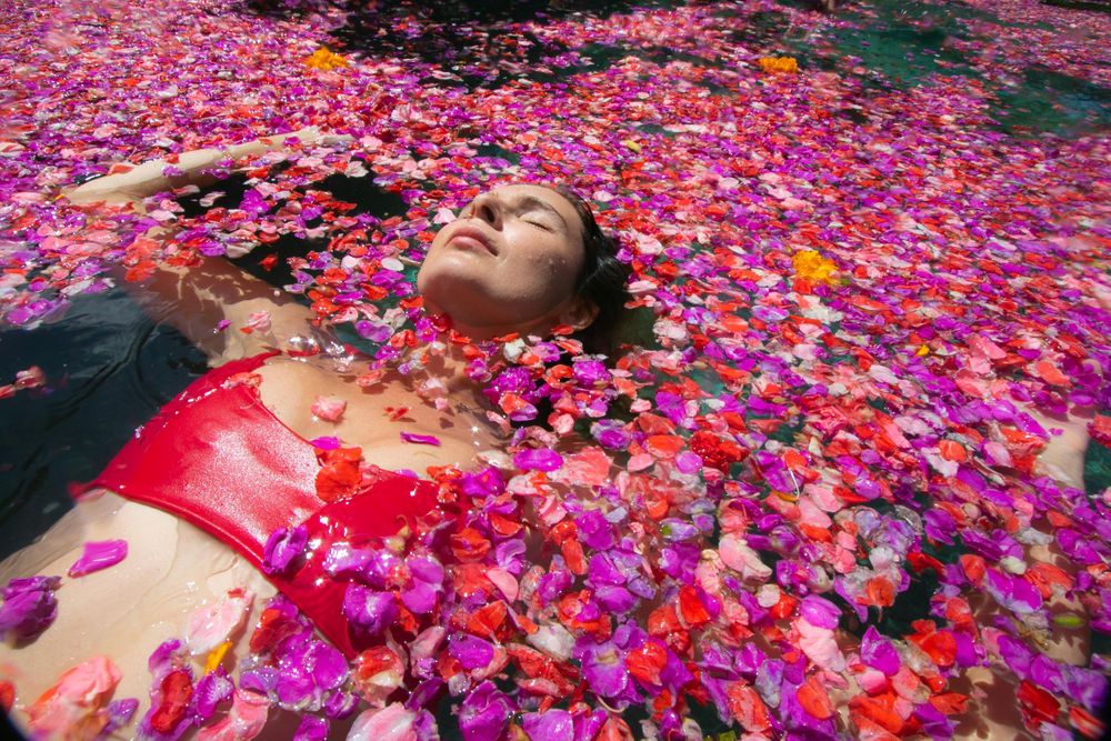 A girl lies in a body of floating flowers