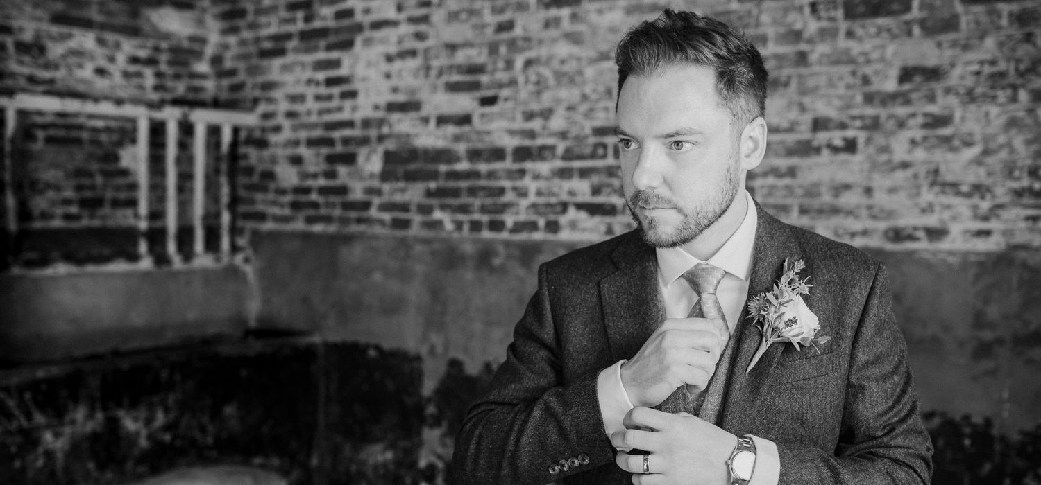 Black and white portrait in rustic brick venue with dramatic lighting.