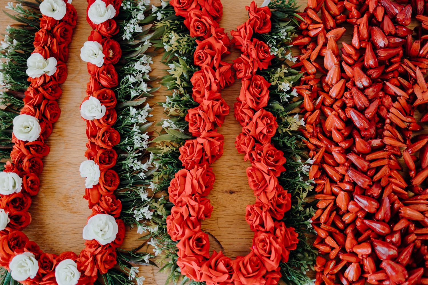 Traditional Hawaiian lei garlands in red and white displayed in rows.