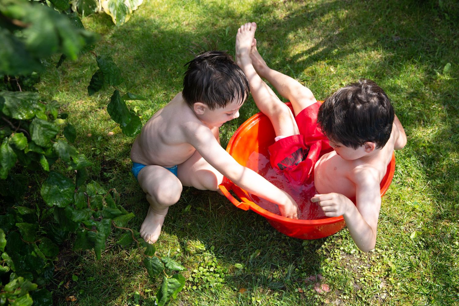 two boys splashing in red bucket