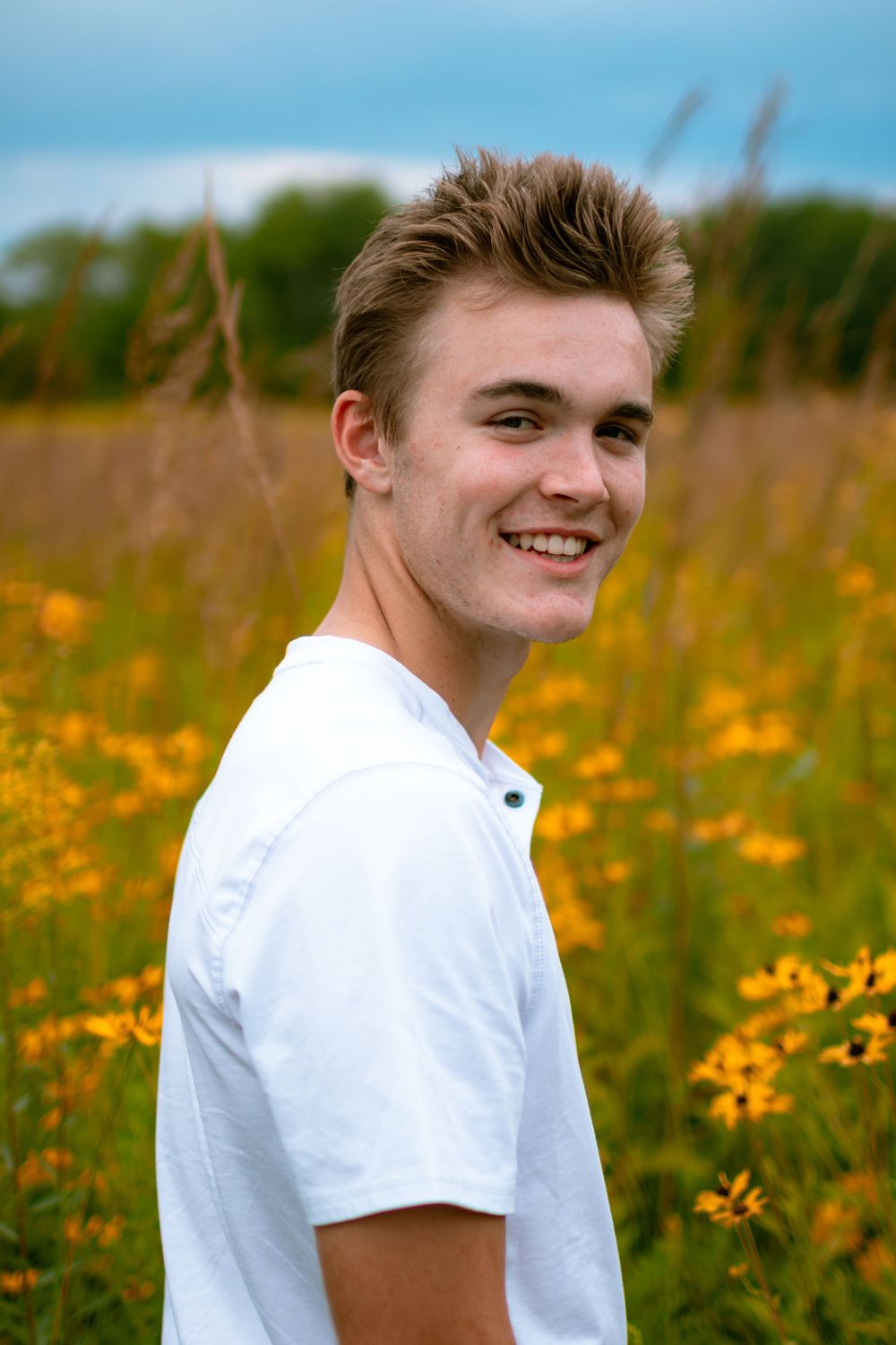 senior boy in grassy flower field