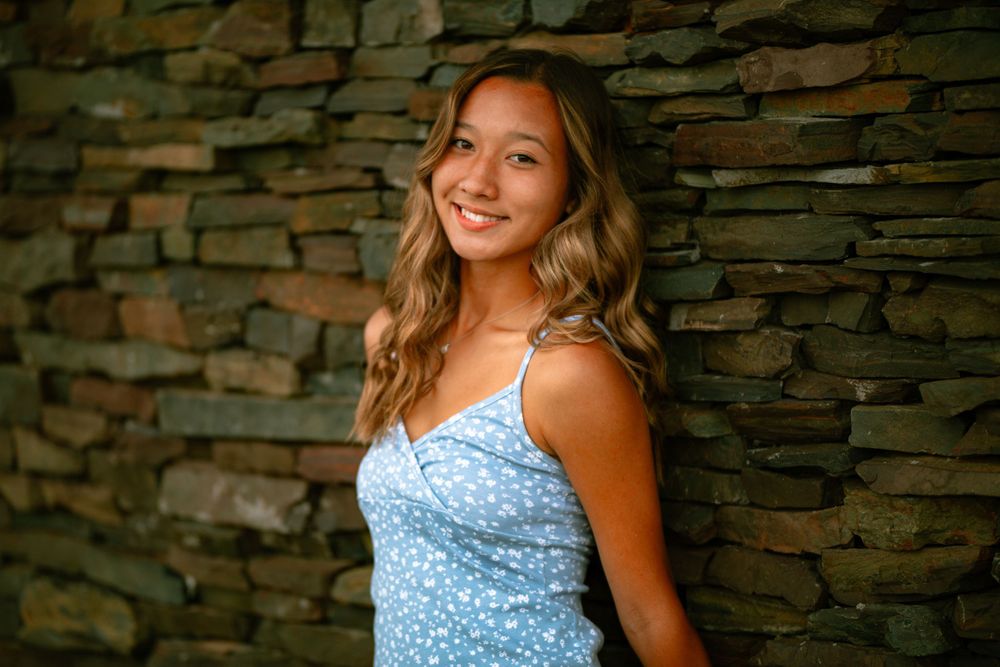 senior girl leaning against brick wall