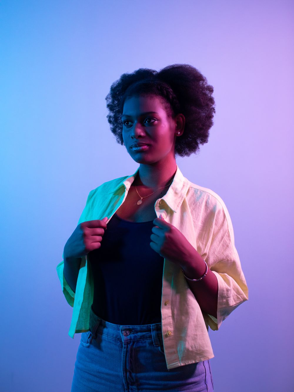 Cross lit magenta and blue studio portrait of a young woman of colour