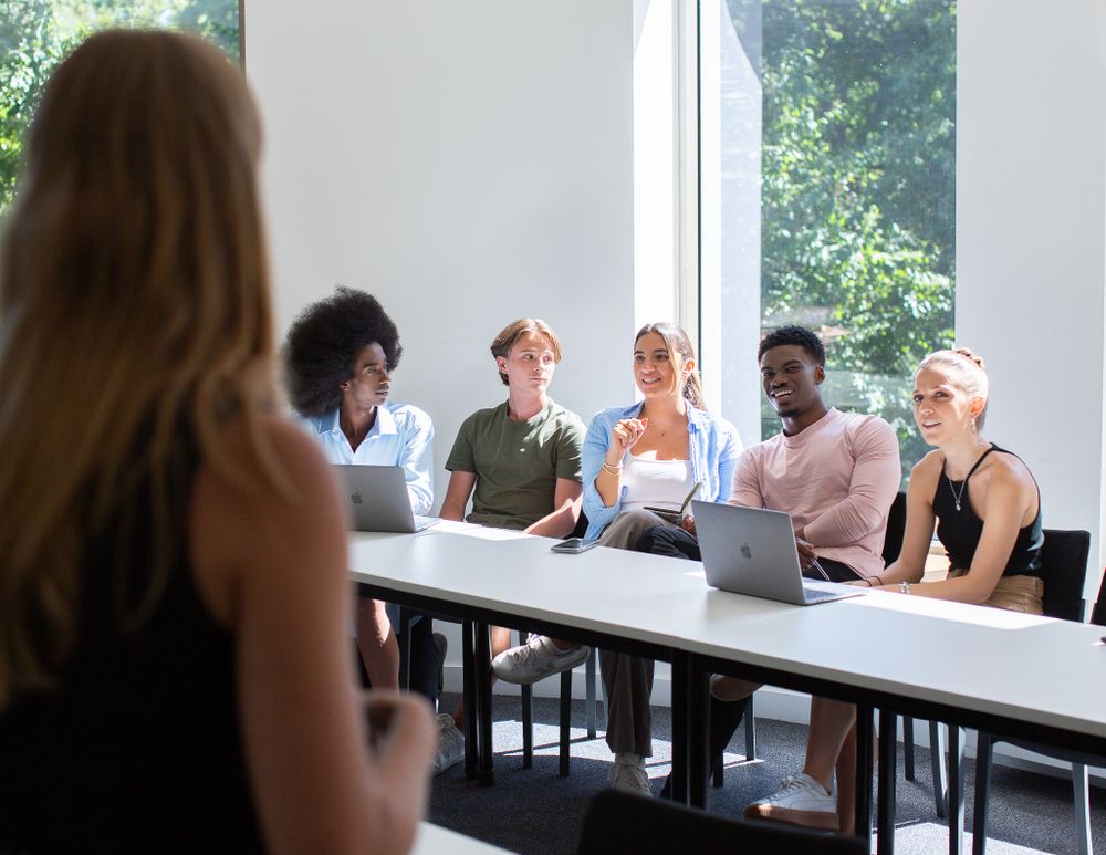 Group of students laugh during a discussion with their tutor