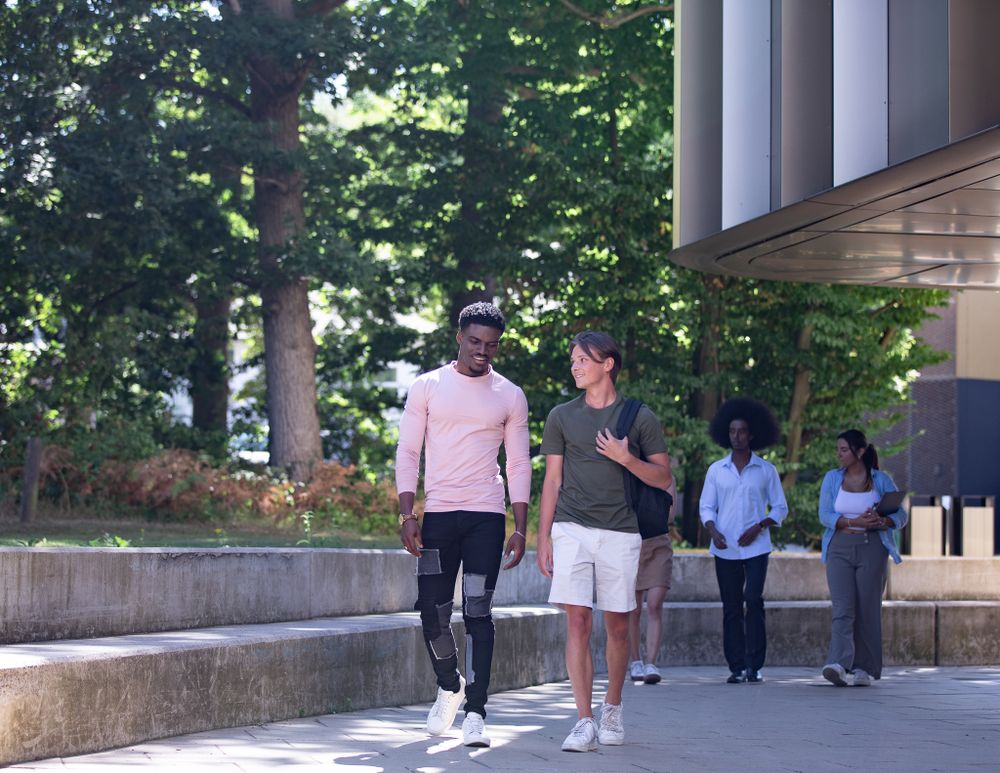 A group of students chat and laugh as they walk across campus