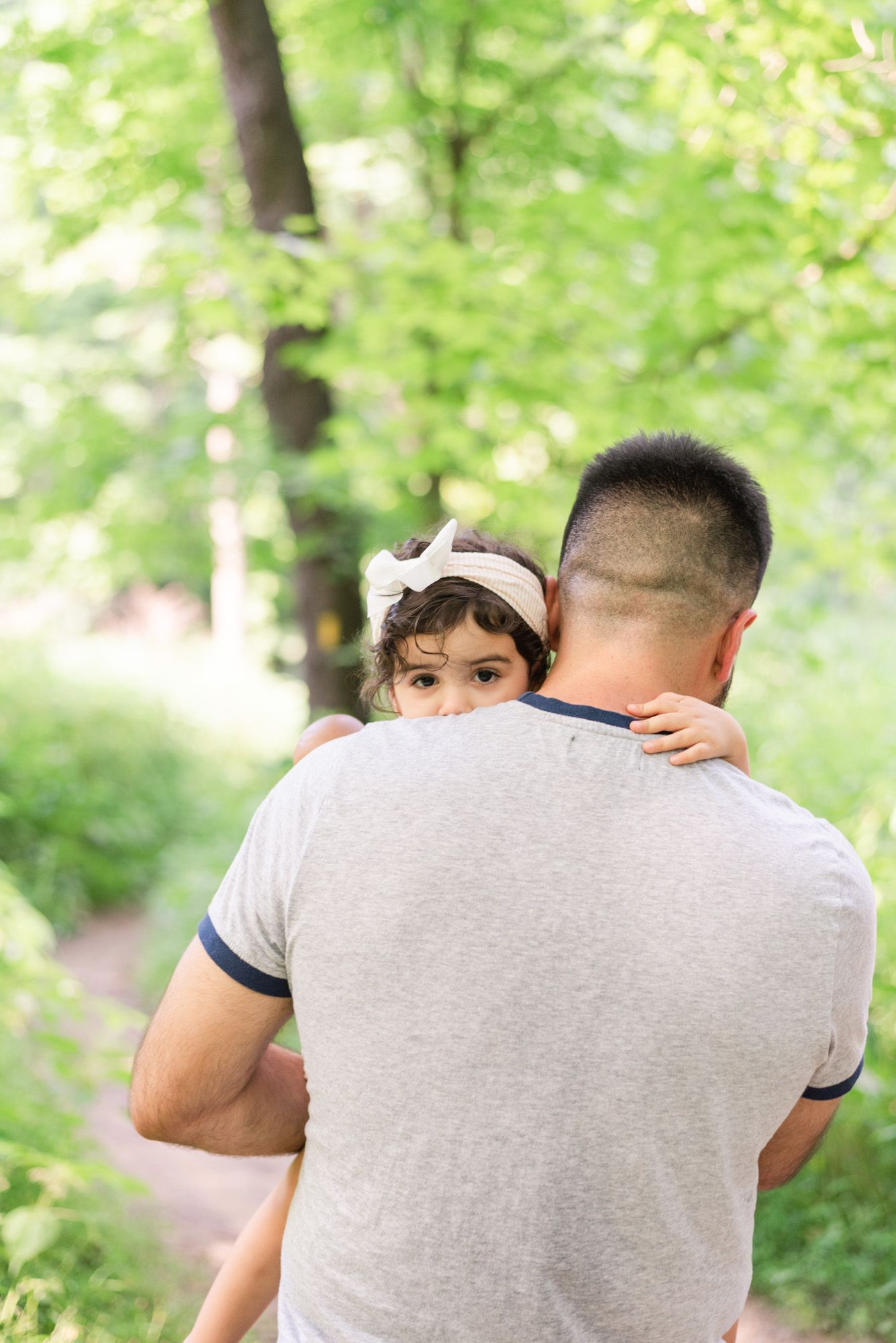 Toddler looking over dad's shoulder in woods in Pittsburgh, Pennsylvania