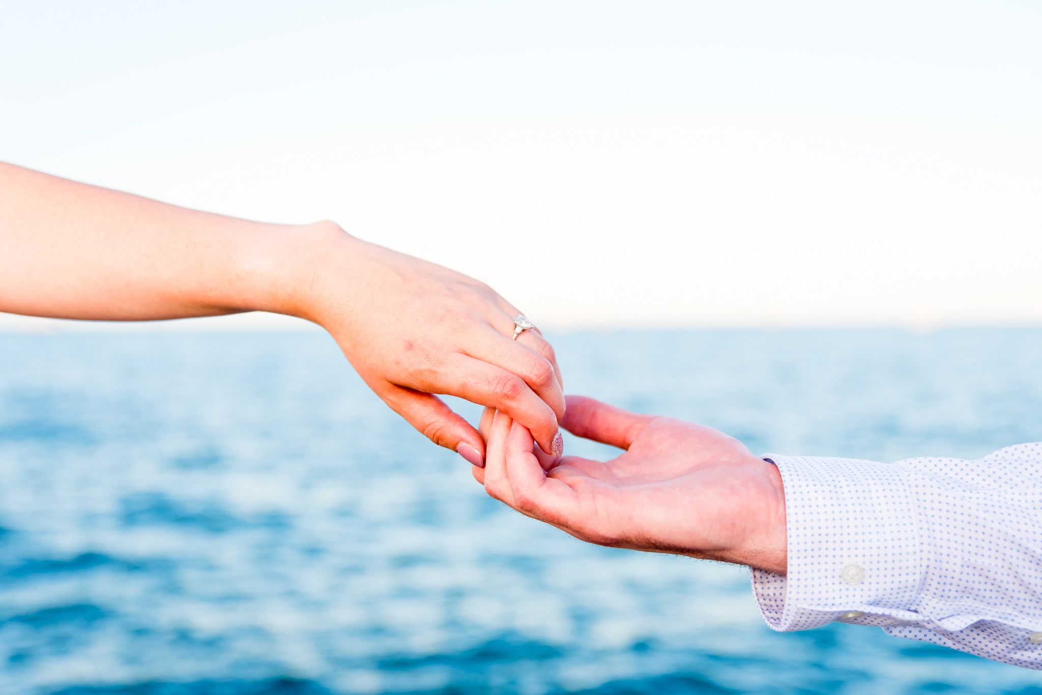 bride and groom touching fingertips in front of Lake Michigan