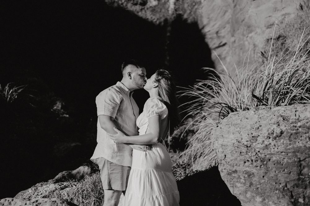 A black and white photo of a couple embracing against dramatic canyon walls.