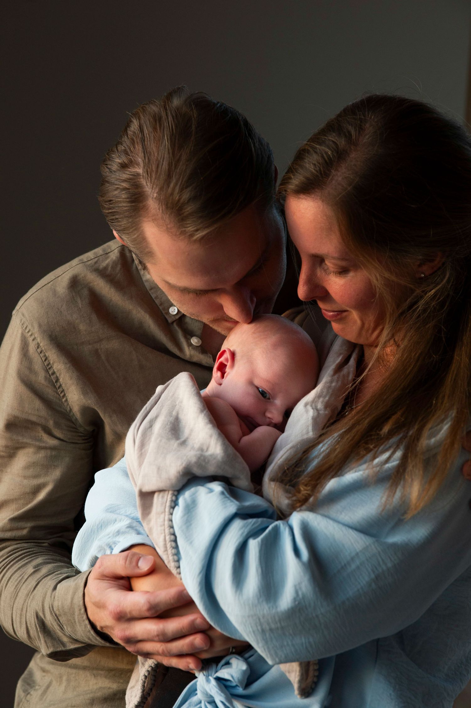 Nyföddfotografering i hemmiljö, pappa pussar sin son på pannan.