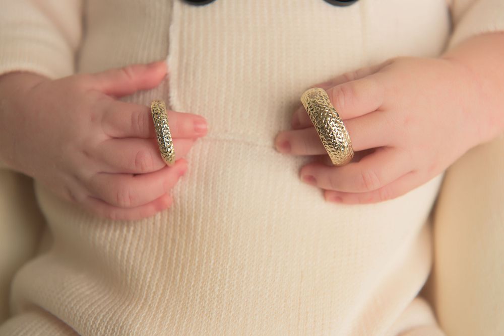 Close-up of small hands holding glittery gold decorative items.