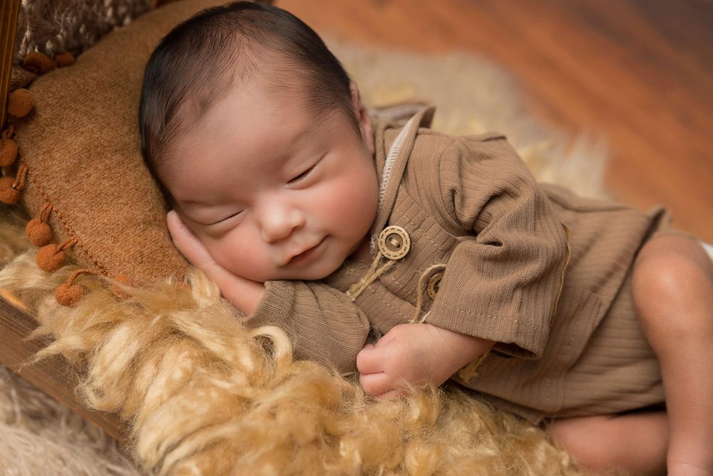 Sleeping infant in tan outfit on soft furry blanket.