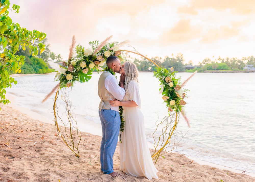 Couple kissing under Hawaiian wedding arch