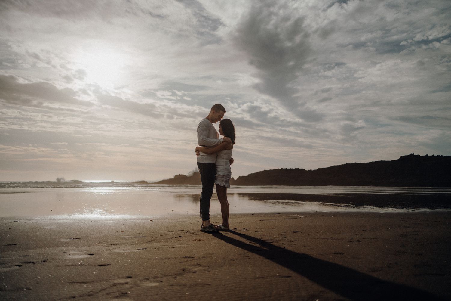 A couple in Karekare Beach's sunset in their post-wedding photoshoot with Apertured Media-Auckland Wedding Photographer.
