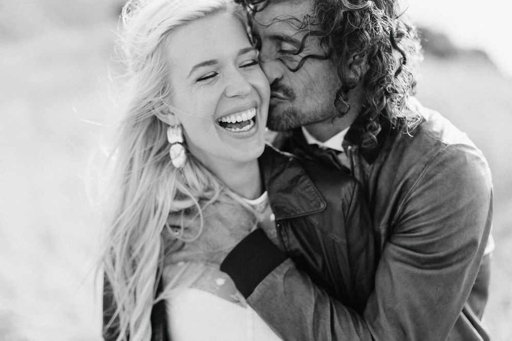 A romantic black and white portrait of a couple sharing a joyful moment on their wedding day.