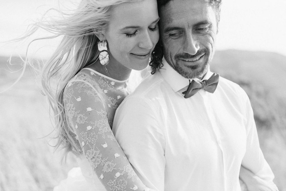 Black and white portrait of a happy wedding couple with wind-swept hair.