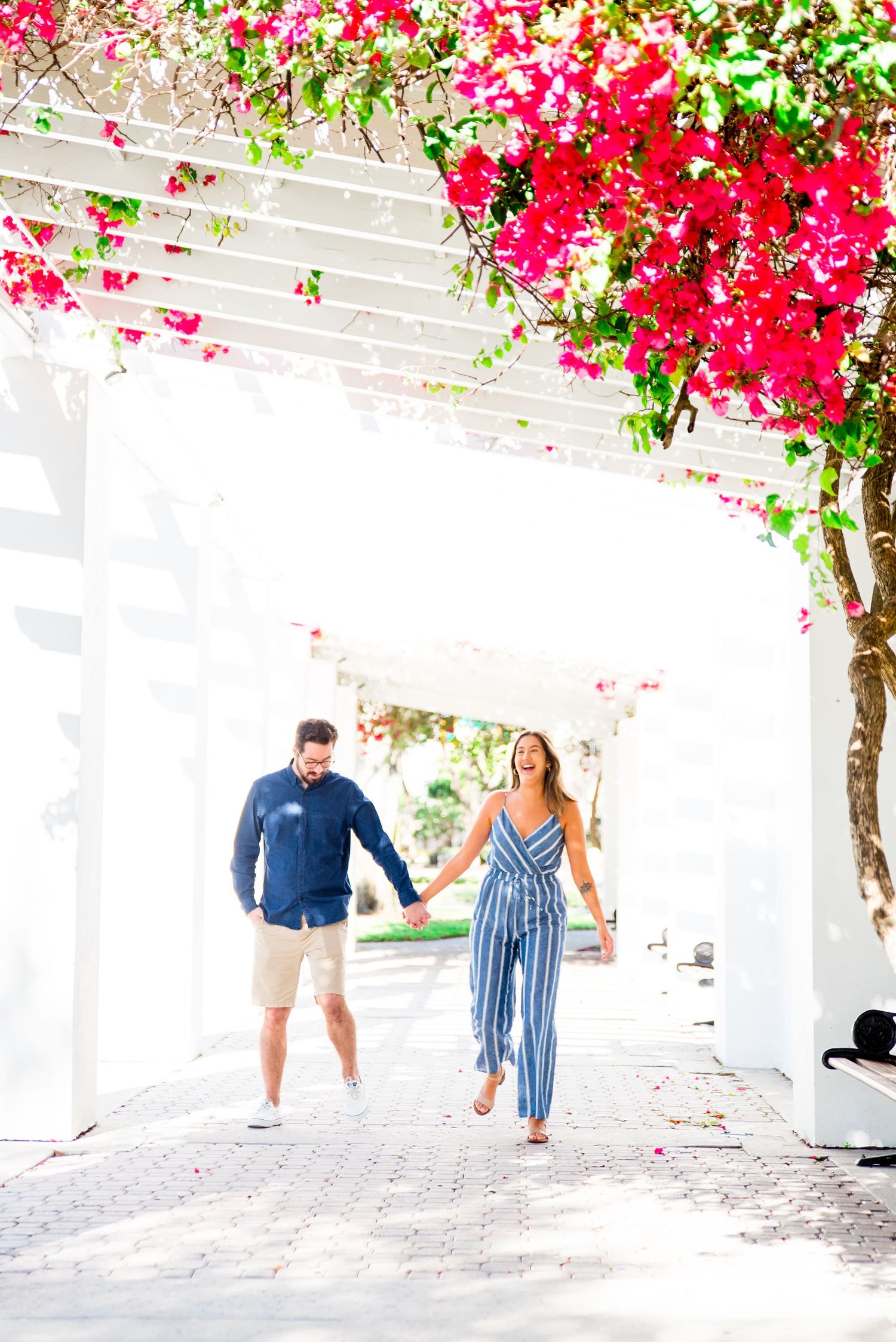 young couple in blue outfits walking and laughing at Vinoy Park St Pete engagement photos