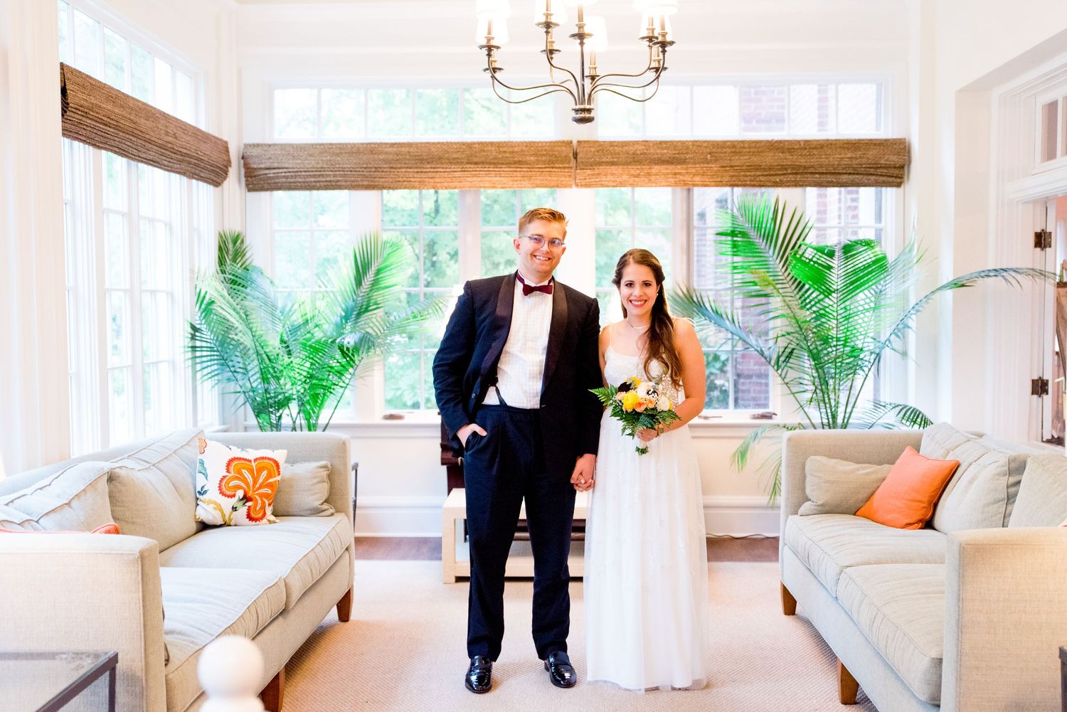 bride and groom hold hands and stand together in the sunroom at the Woman's Club of Evanston on their wedding day