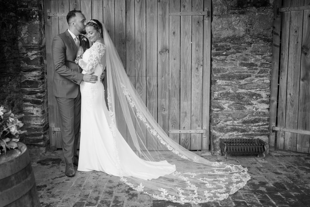 bride and groom, black and white photo in barn in front of wooden door. Rustic country wedding
