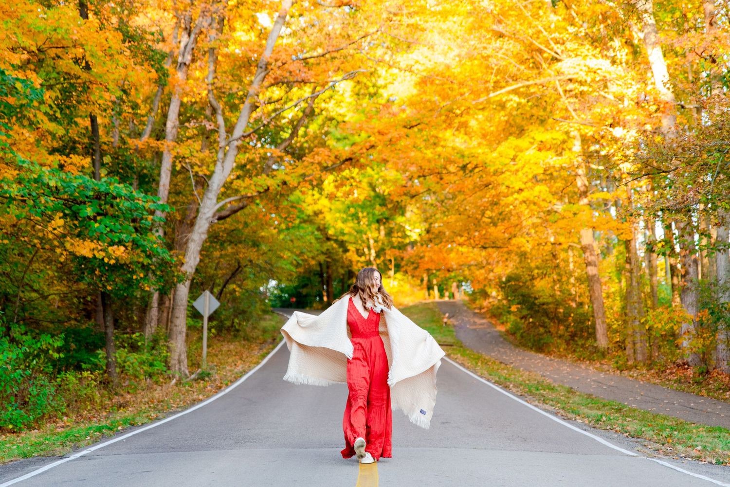 girl in orange jumpsuit dancing with a white blanket under yellow trees at Sharon Woods park in Cincinnati Ohio