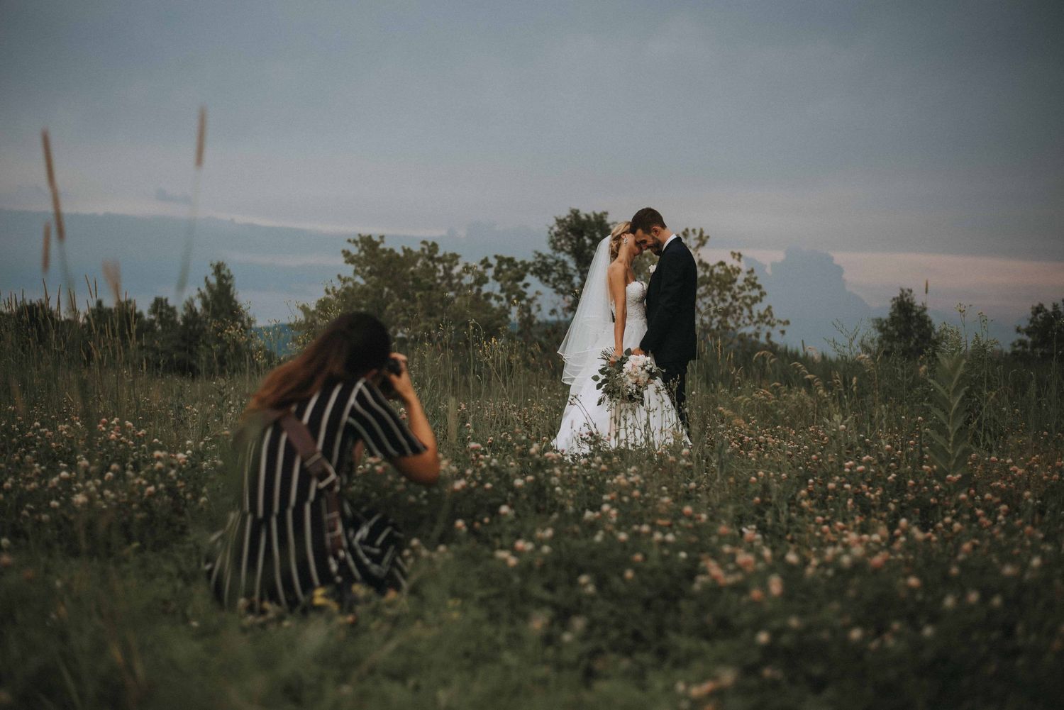 Raphaëlle Granger laying down in a flower field to get the perfect angle for this wedding session