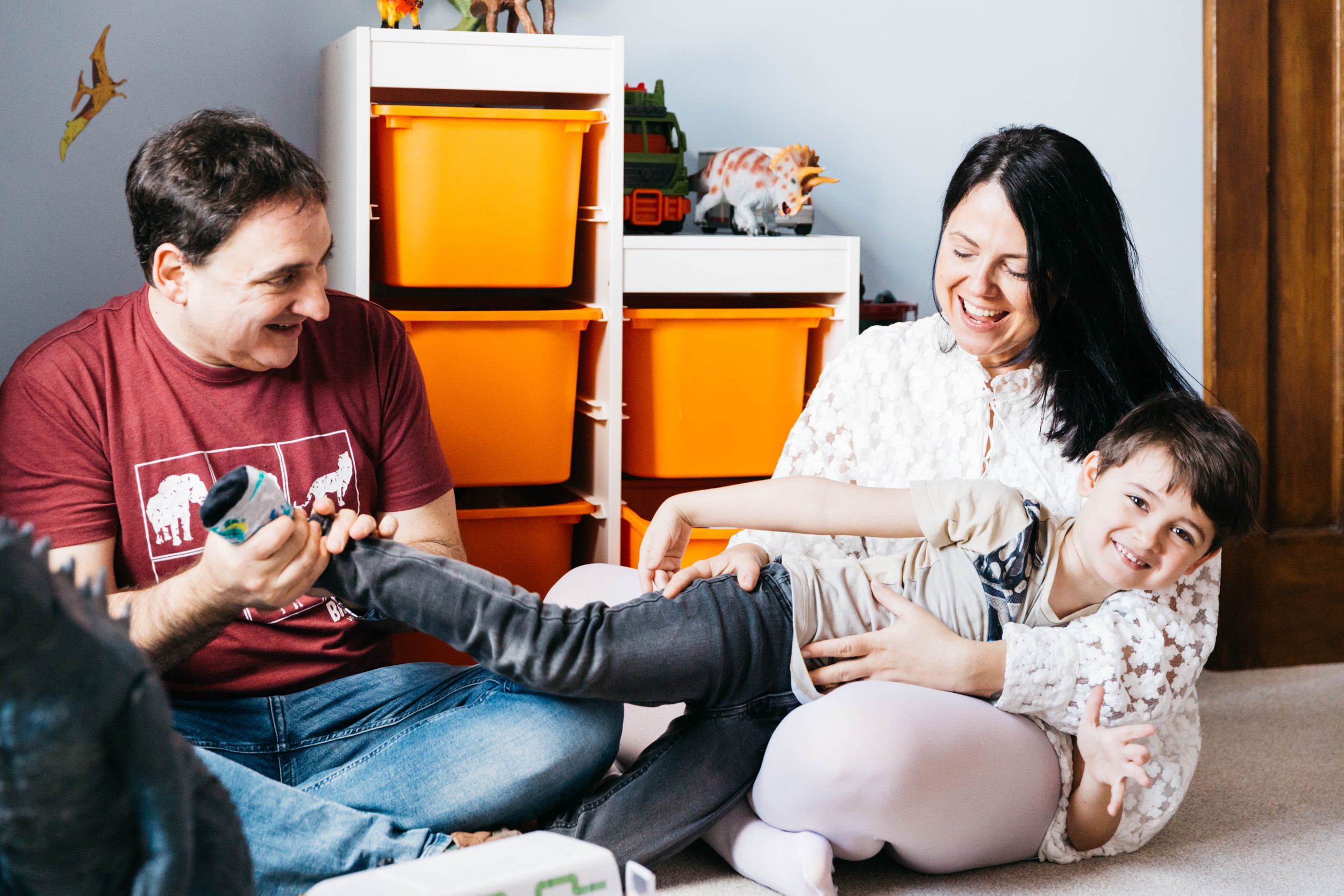 family of three at home with their dog joking around in bedroom