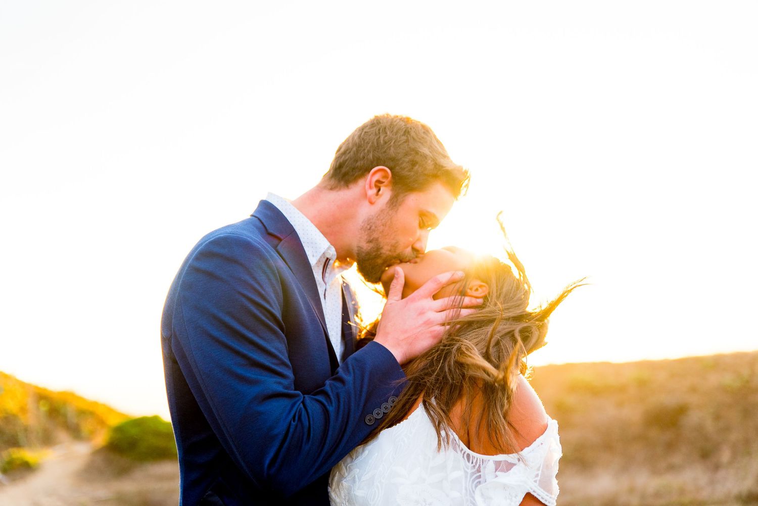 engaged man and woman kissing in the wind at sunset near Golden Gate Bridge San Francisco