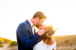 engaged man and woman kissing in the wind at sunset near Golden Gate Bridge San Francisco