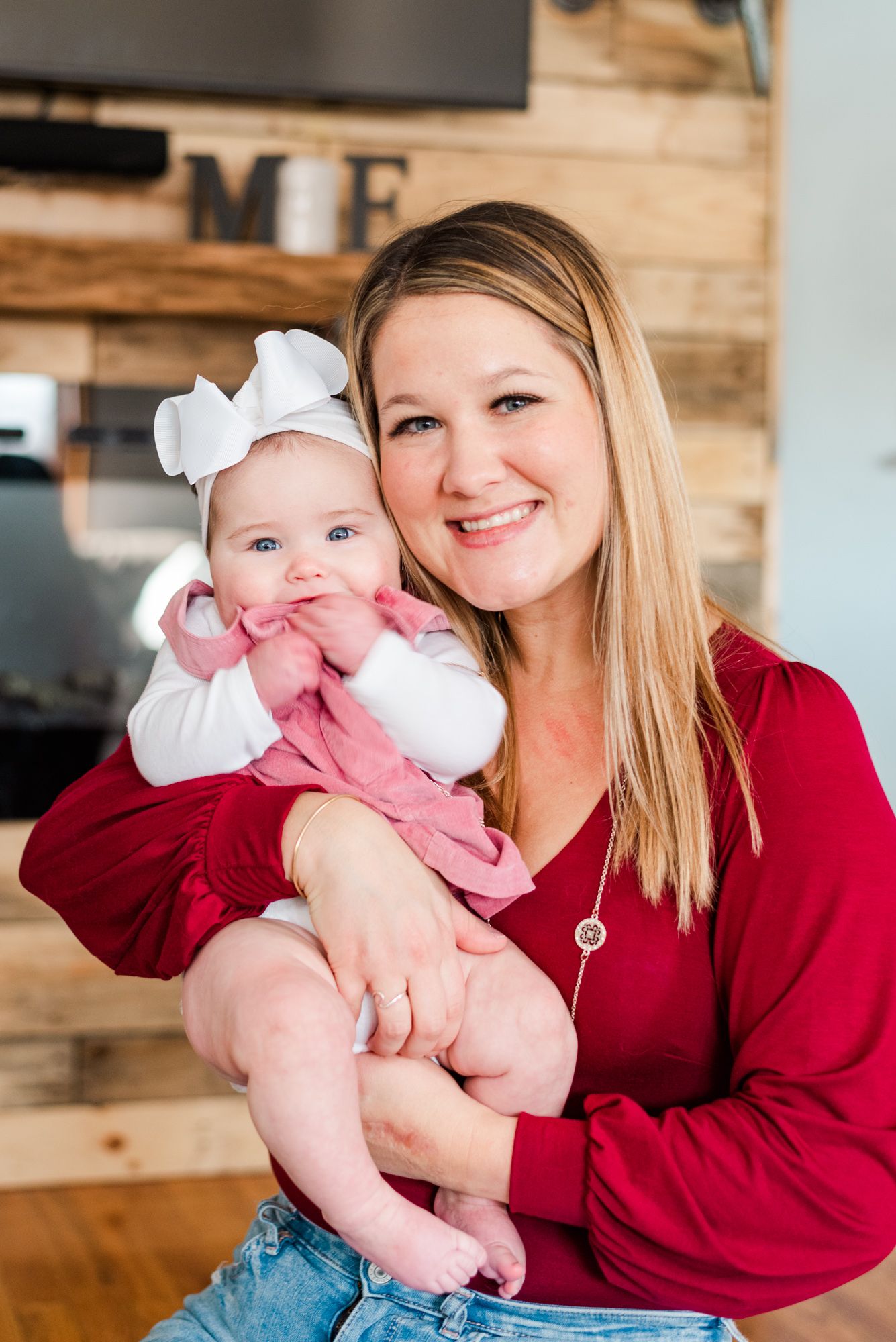 Lifestyle family photoshoot in the home with mom holding baby wearing bow in Gibsonia, Pennsylvania