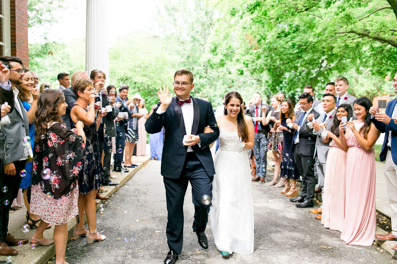 bride and groom holding hands smiling and walking through bubble exit for Woman's Club of Evanston brunch wedding