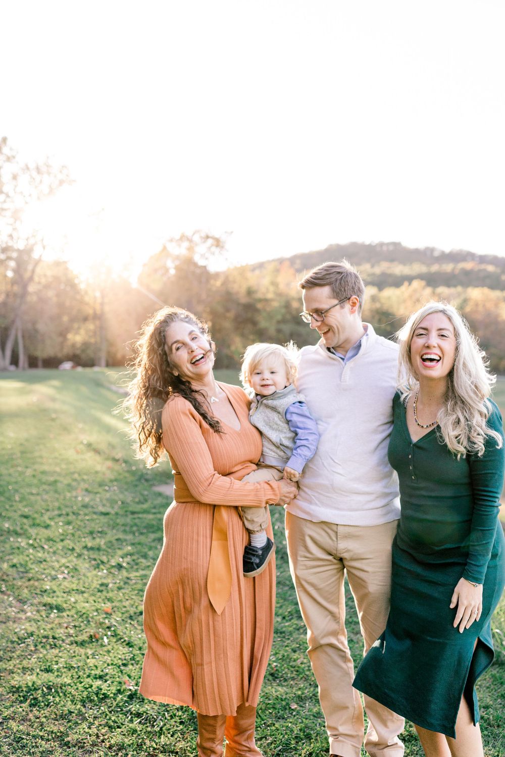 Group portrait of people laughing together in a sunny field at golden hour.