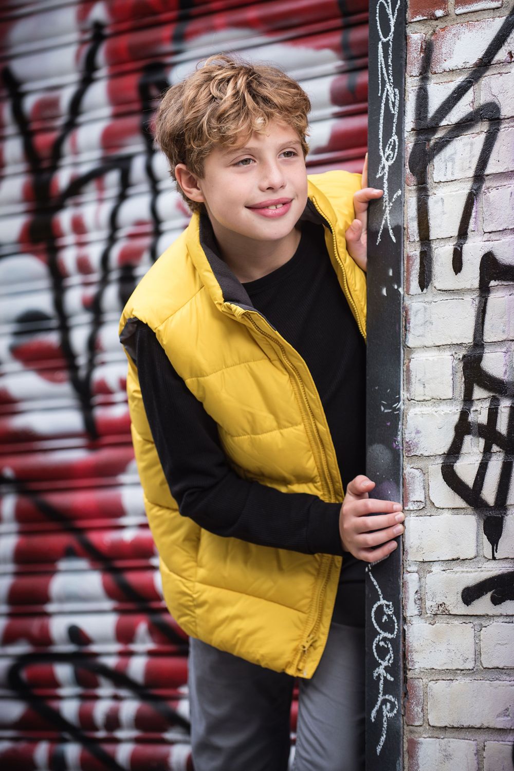 Young male model wearing bright yellow vest with graffiti background