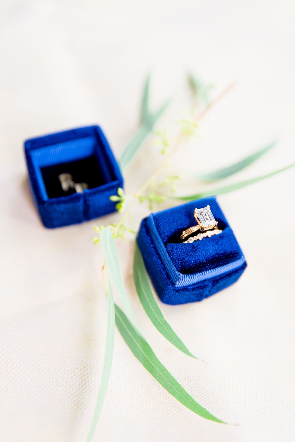 yellow gold emerald cut engagement ring in a blue Richter and Phillips box next to some loose greenery