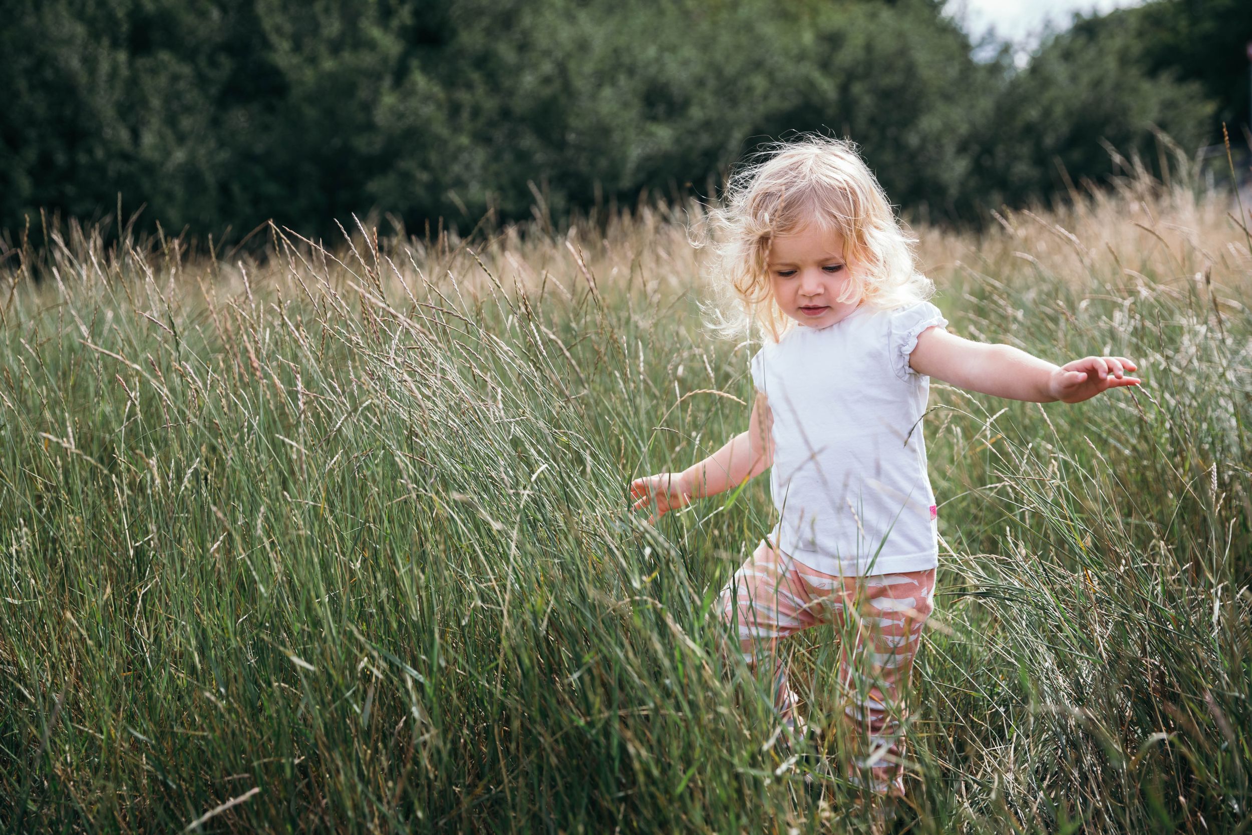 little blonde girl running through grass