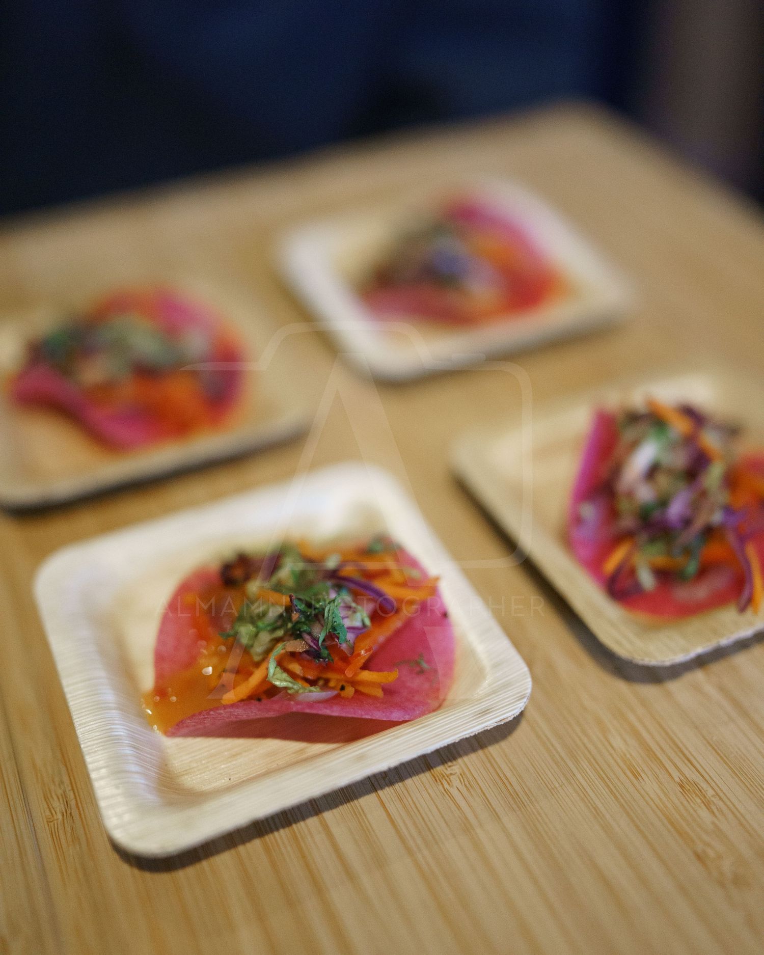 Fresh tuna appetizers garnished with microgreens served on disposable wooden plates.