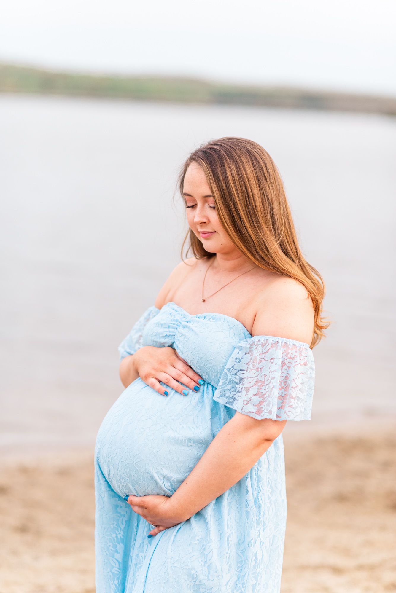 Maternity session with pregnant mother on beach in golden hour sunlight at Moraine State Park, Pennsylvania