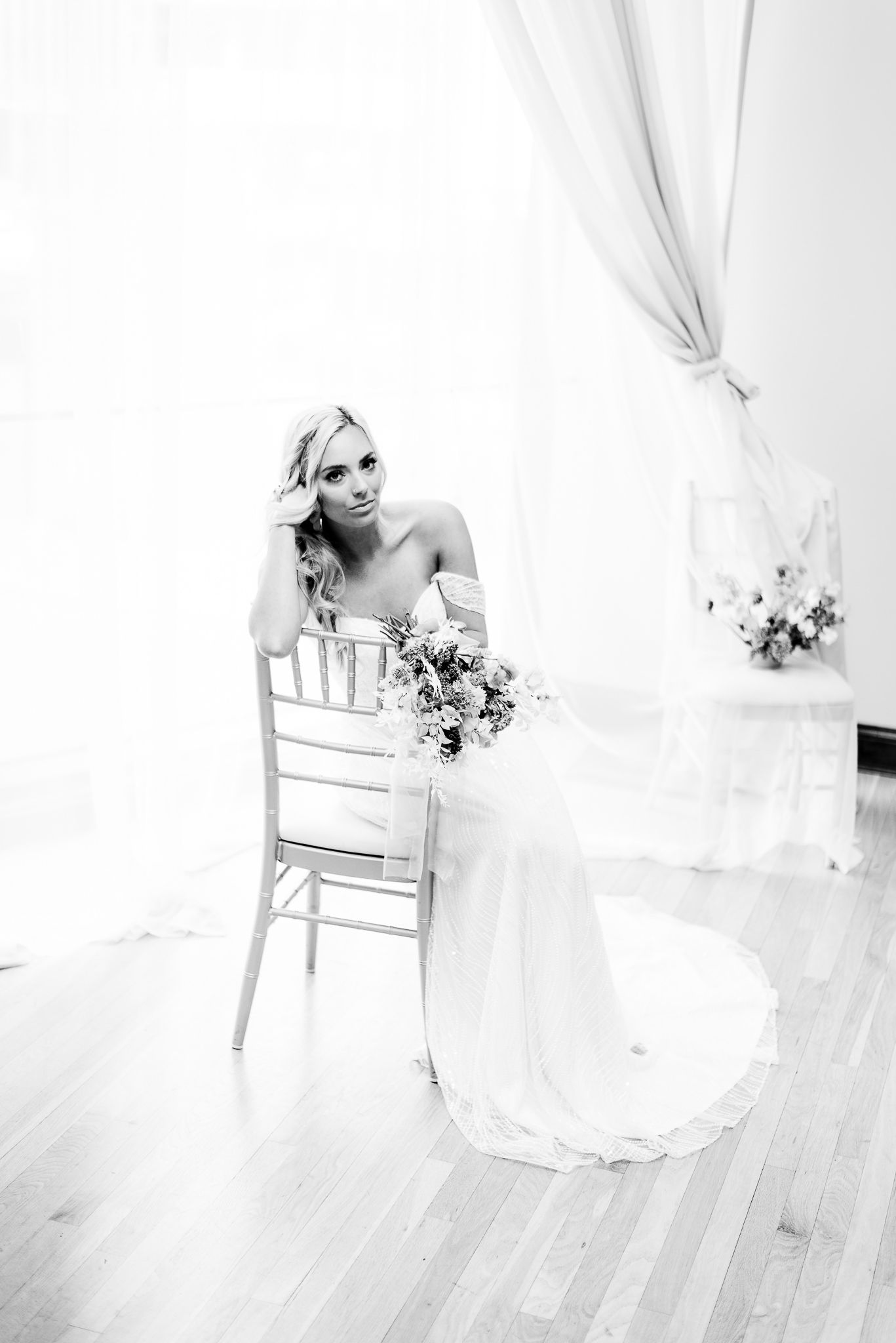 bride sitting in chair with bouquet looking at camera
