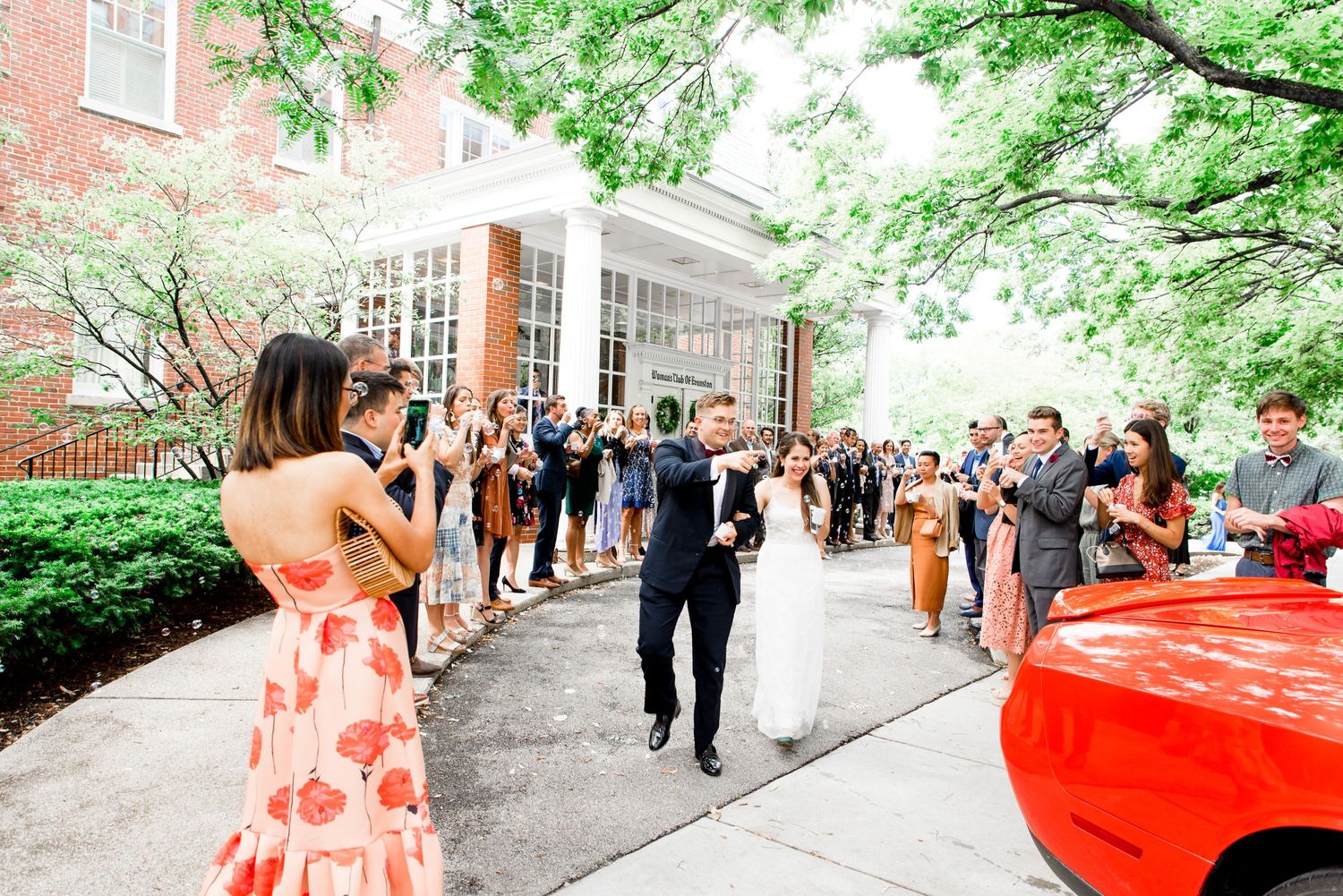 bride and groom walking through wedding guests for grand exit and going to an orange getaway car