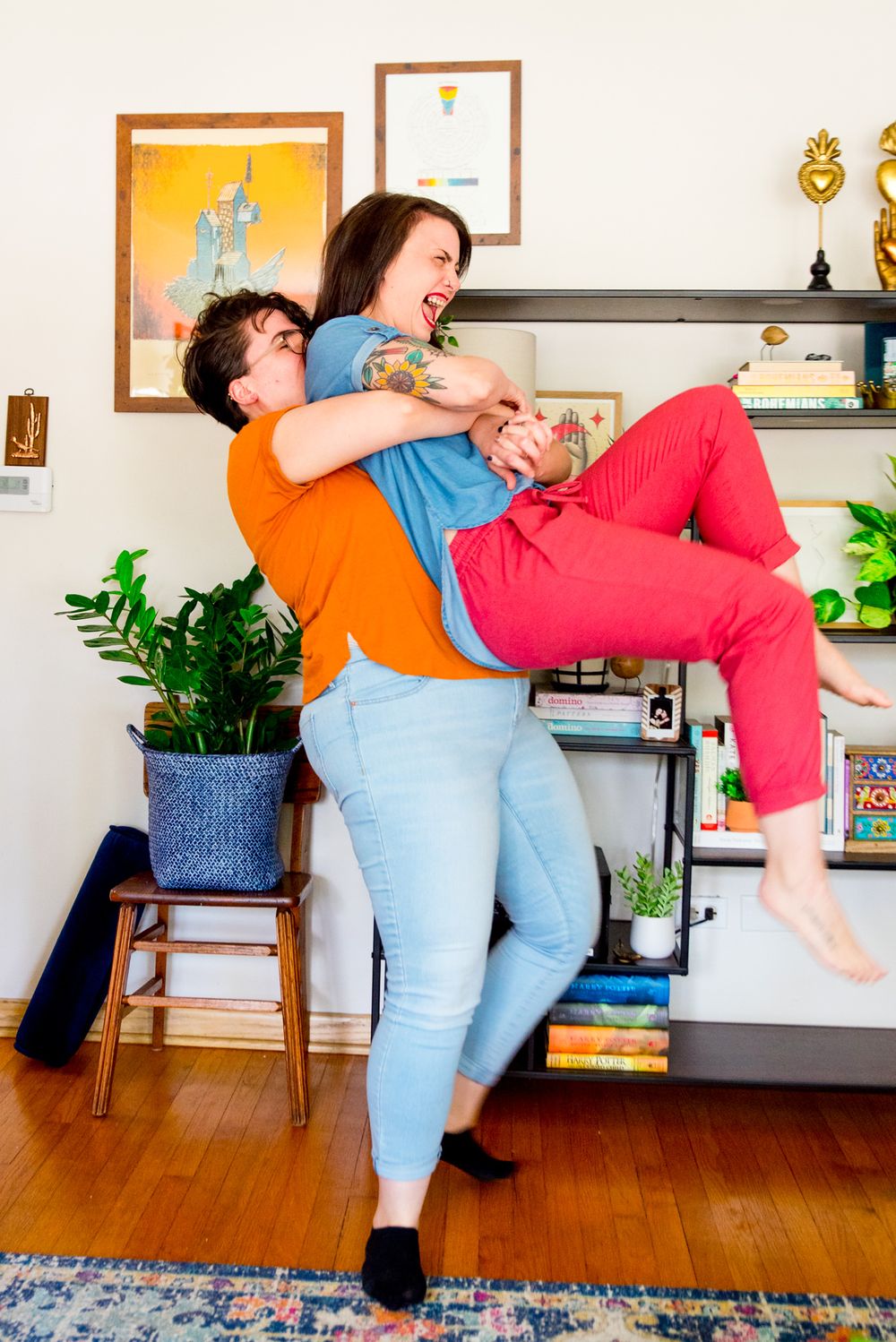 woman in orange shirt picking up woman in pink pants, laughing and flipping her hair for Chicago same sex couple photos