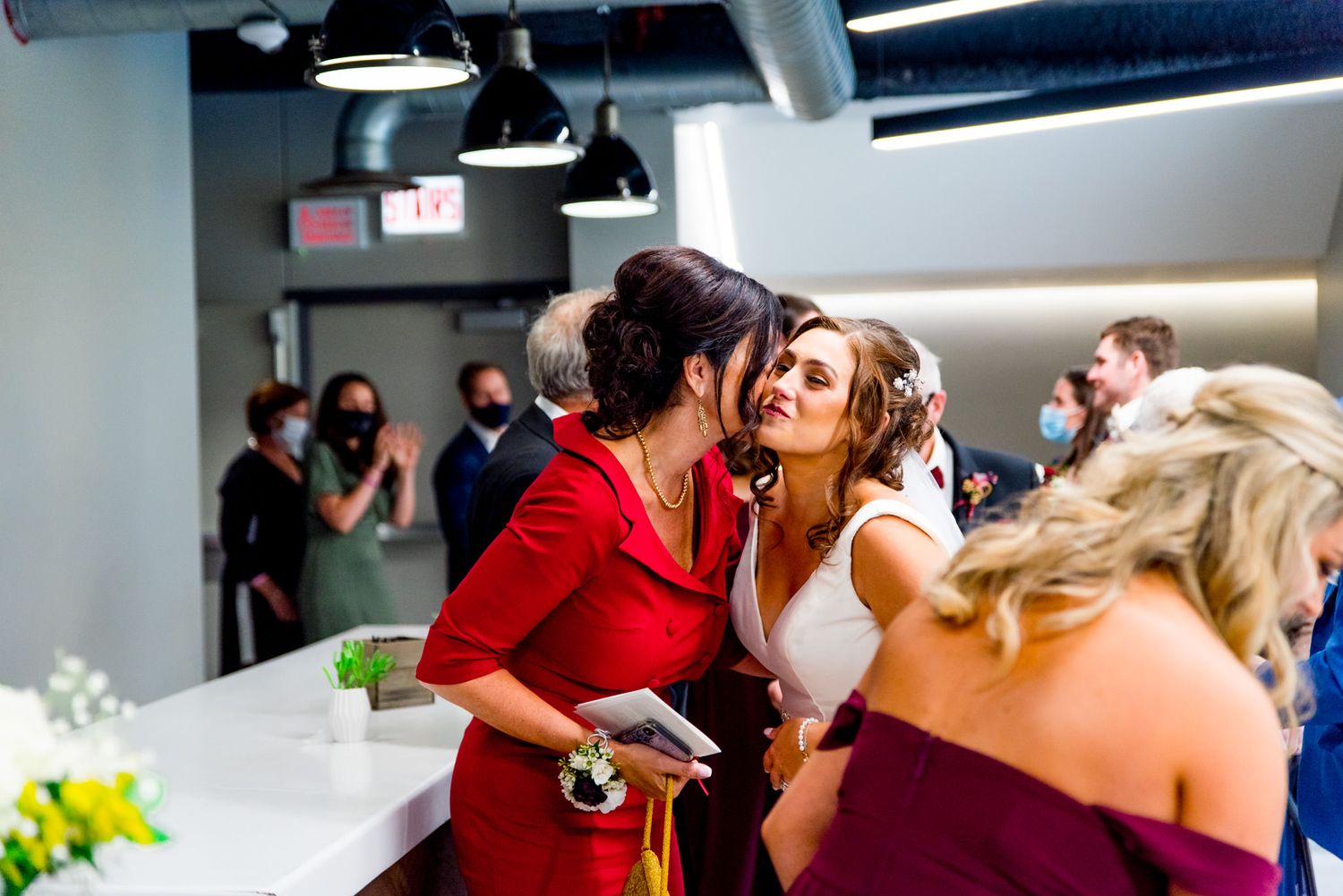 bride hugs guest in red blazer for autumn wedding ceremony