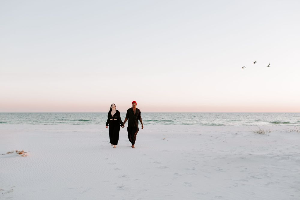 couple holding hands and walking along the beach during their Destin engagement photoshoot