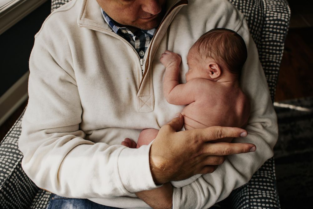 Vanourny Newborn Session Lifestyle Photography Kansas City Father with newborn on chest newborn hand clutching shirt