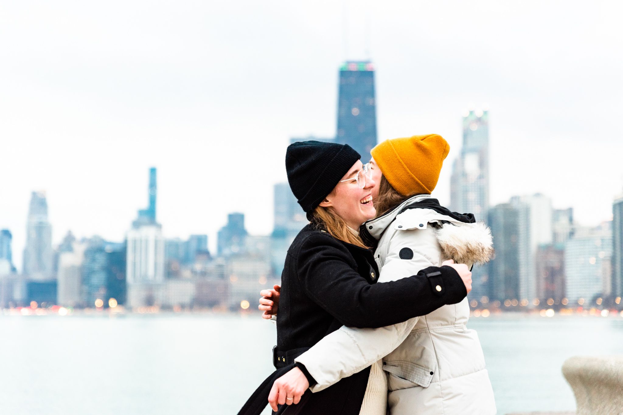 two women in winter coats hug after proposal at north Avenue Beach Chicago