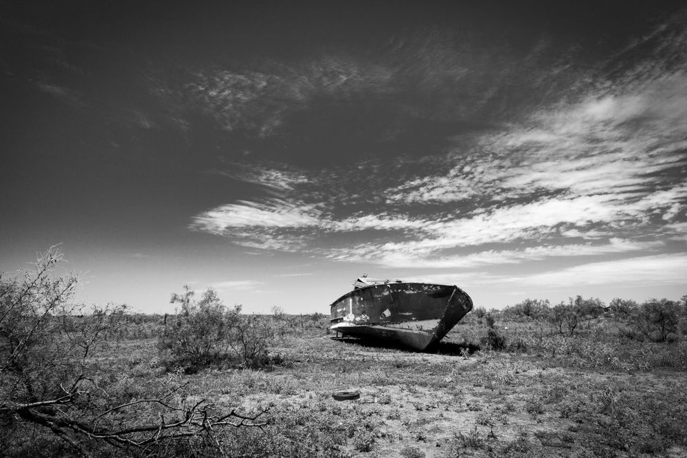 A wooden power boat, sits abandoned in a West Texas pasture.