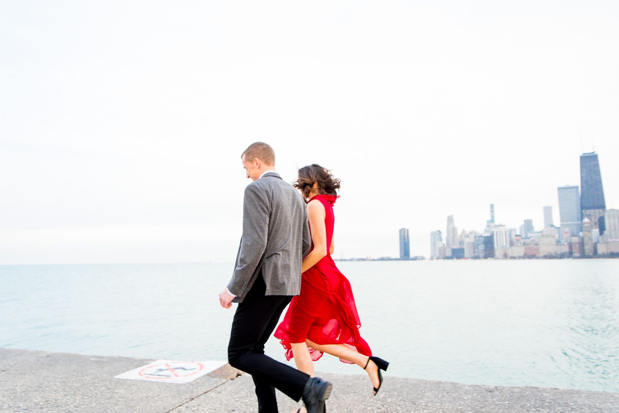 couple running along pier at North Avenue Beach for Chicago engagement pictures