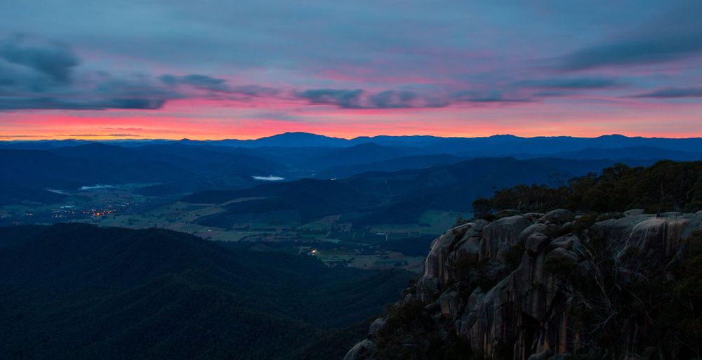 Pink and purple sunset over mountain ranges with dark silhouettes against the colorful sky.