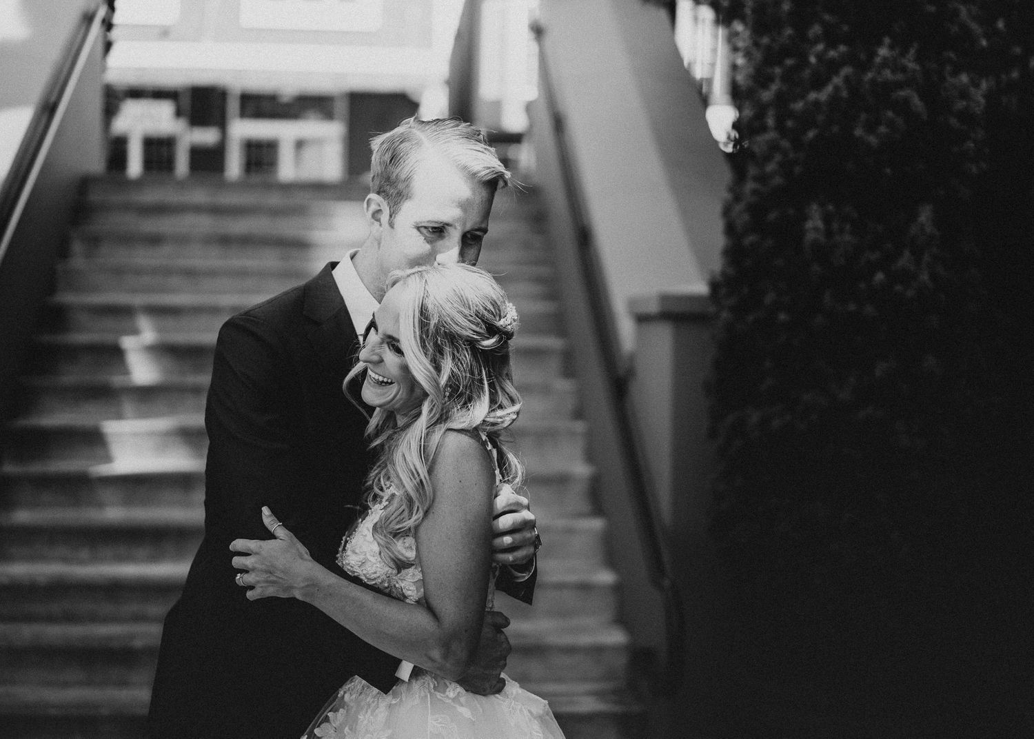 Bride and Groom share a hug and a laugh at the base of the steps of Fifth Street Market in Eugene, OR